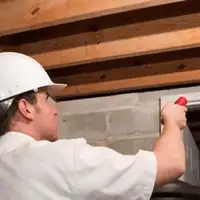 Termite inspection technician checking a basement wall and framing for termite activity in Erie, PA